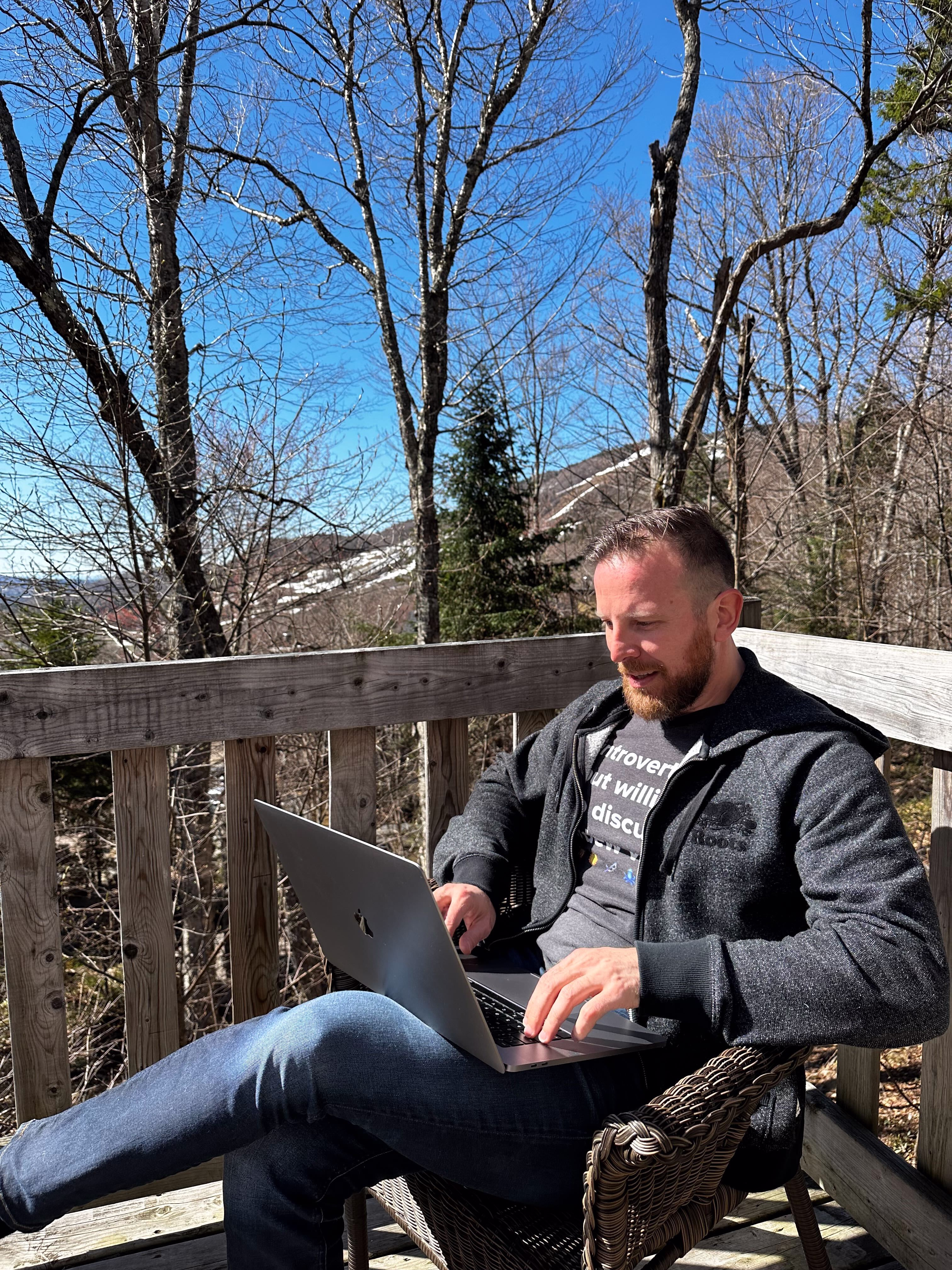 Team member sitting outside with his laptop on his thighs