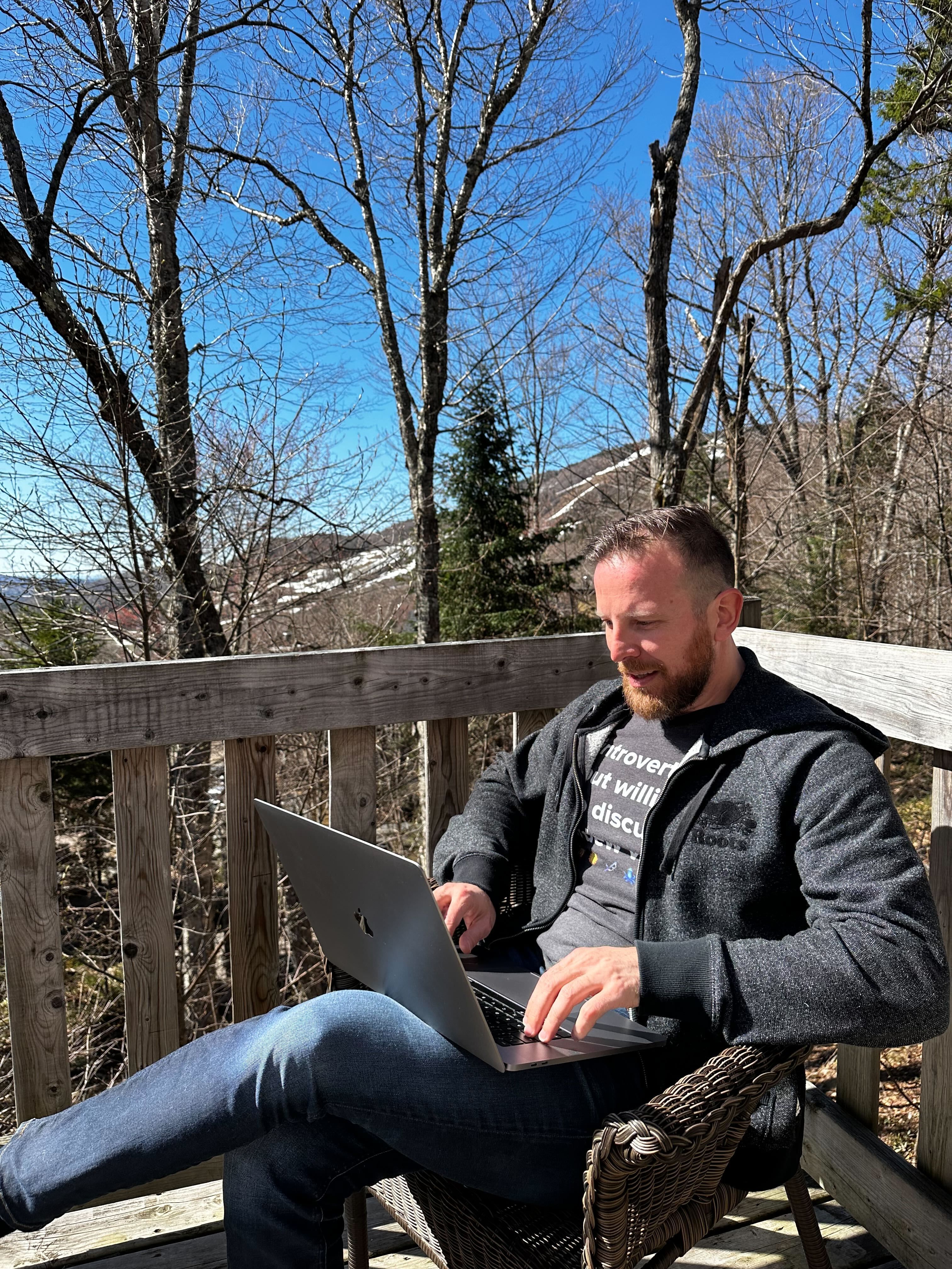Team member sitting outside with his laptop on his thighs
